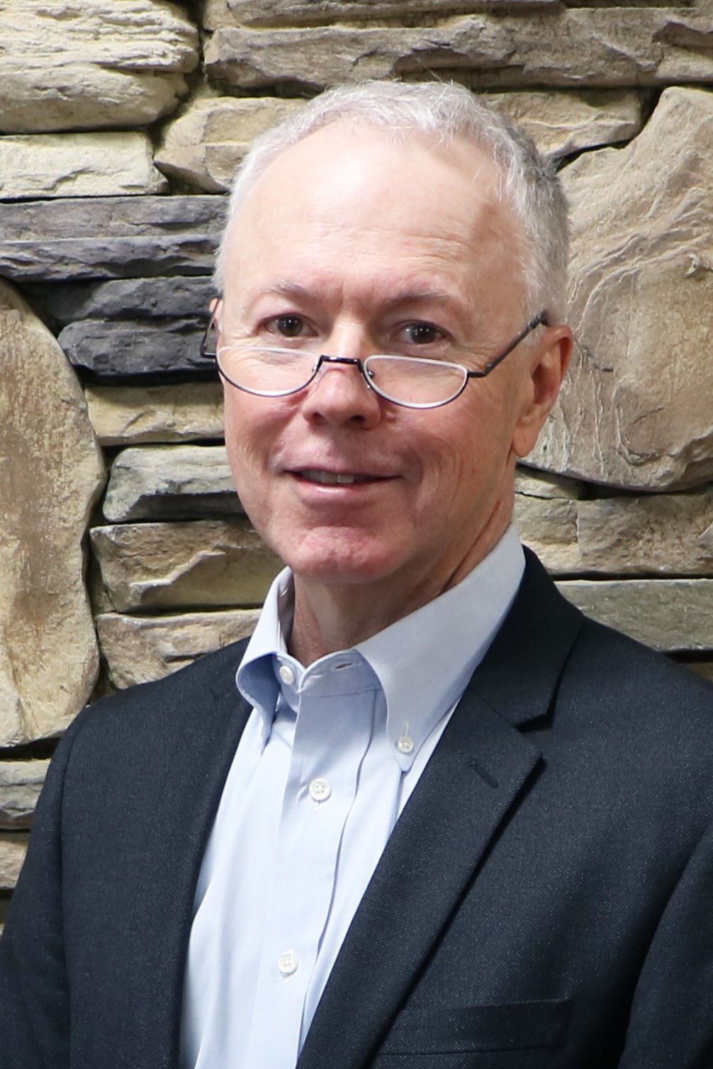 a man standing in front of a brick wall