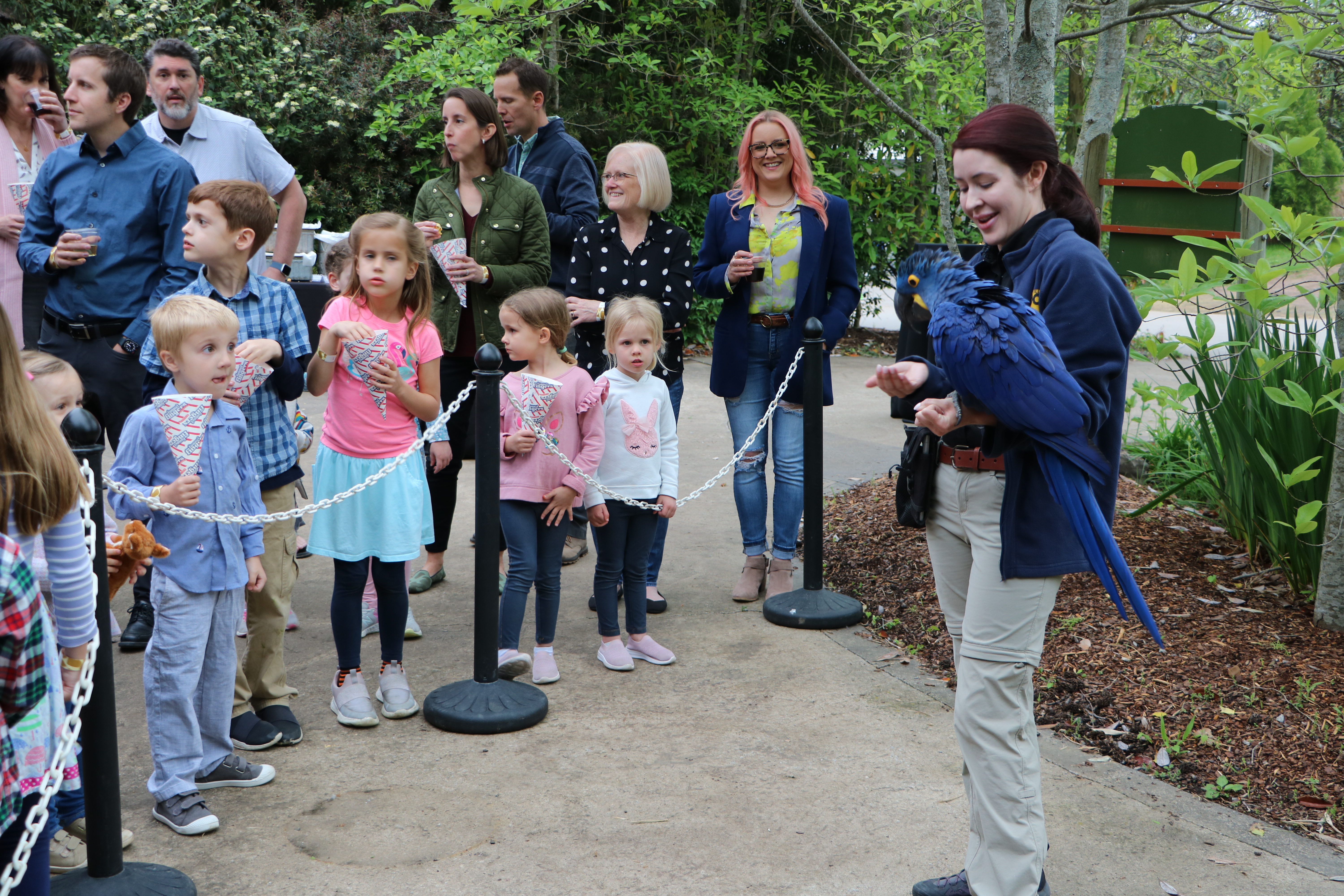 children watching a woman holding a blue macaw