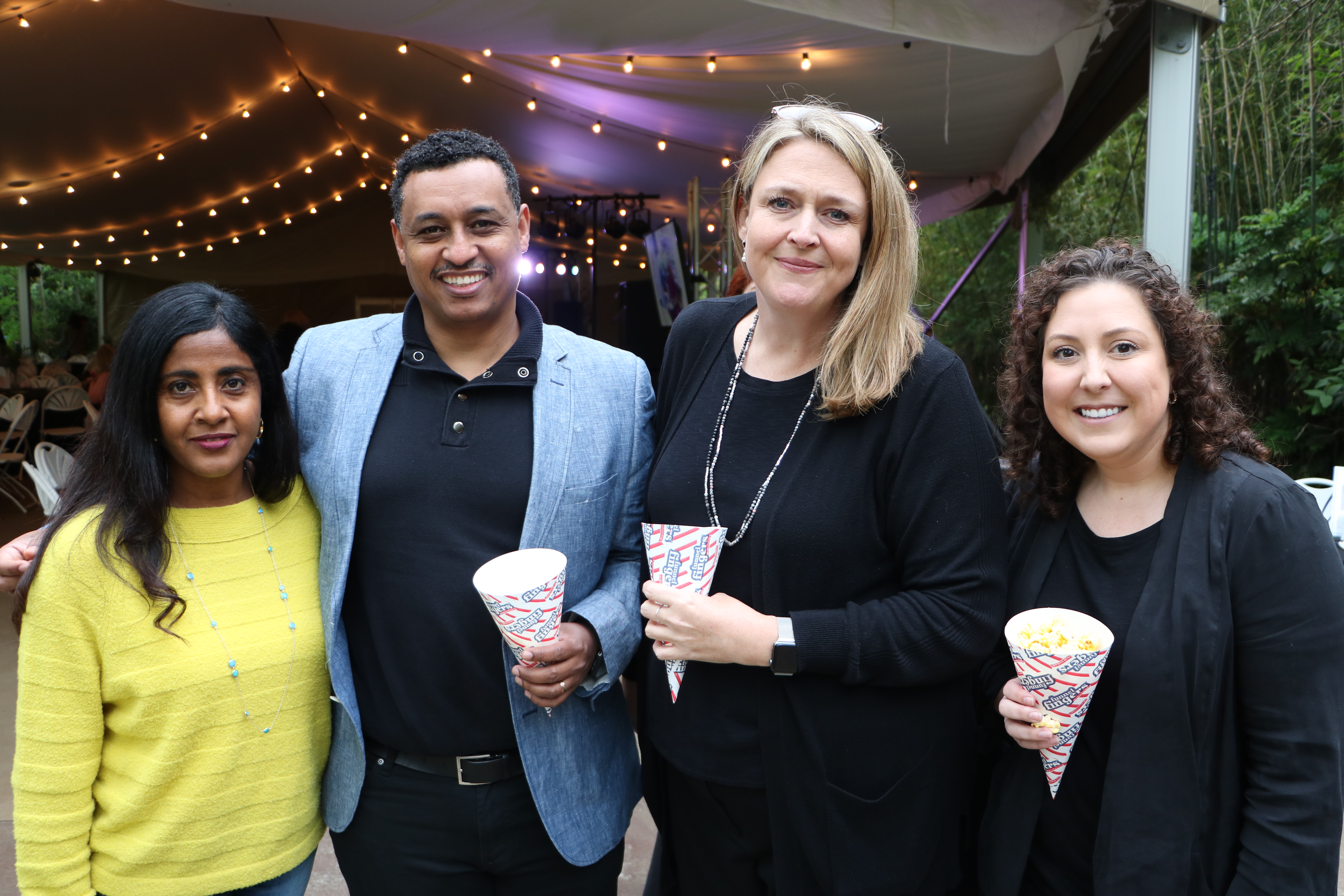 four people standing together holding popcorn