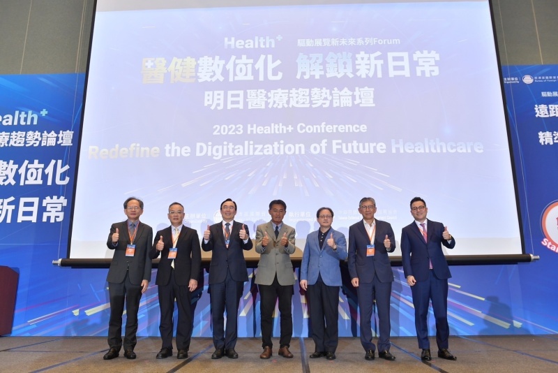 Seven speakers giving thumbs up in front of a conference title screen,