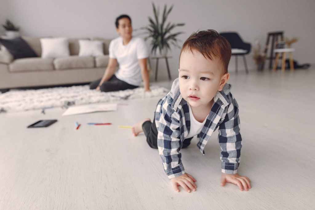 child crawling with adult in background