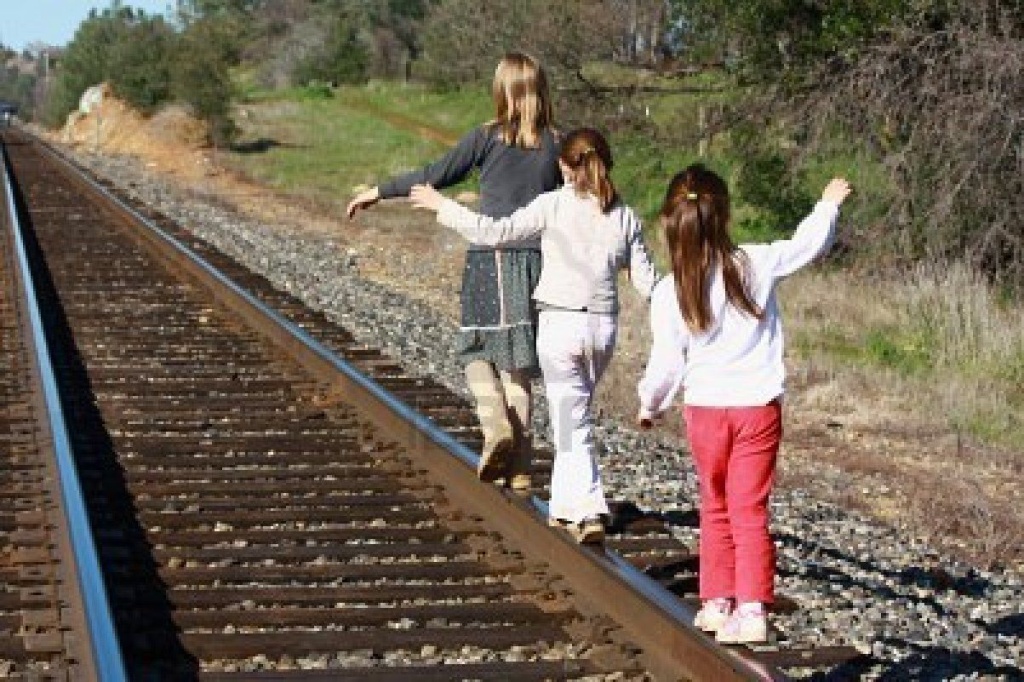 two kids walking on railroad tracks