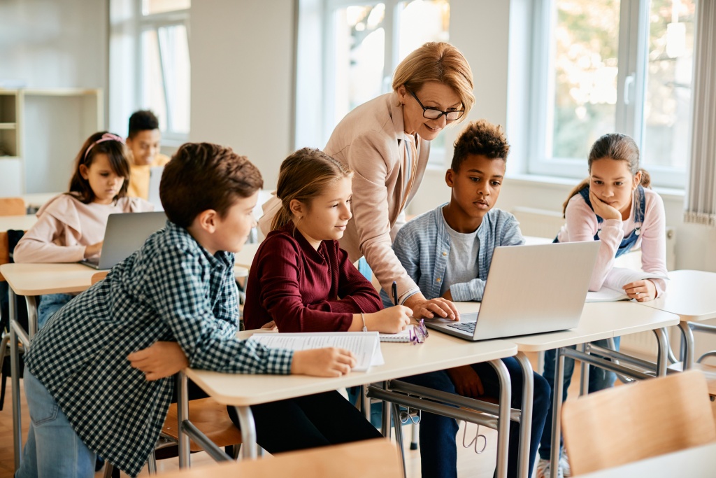 teacher and students looking at laptop